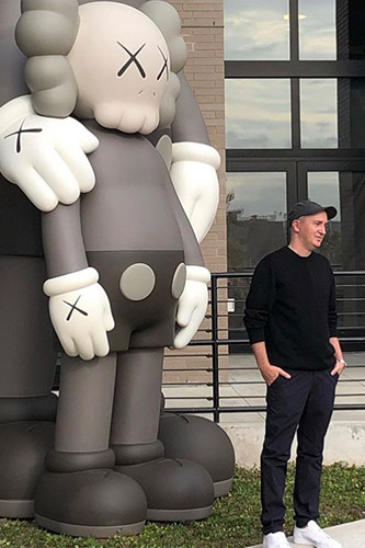 Brian Donnelly, aka KAWS, with his 'Waiting' Companion sculpture at The Greenpoint, Oct 2019.